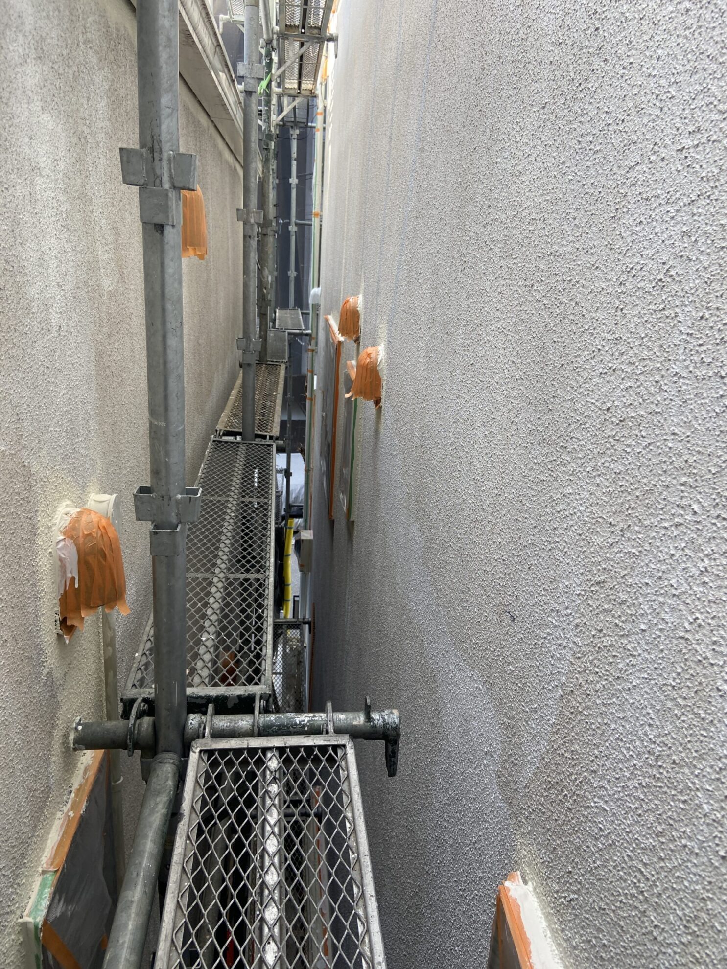 横浜市で隣家との距離が近い住宅に足場を設置して外壁塗装を行う様子